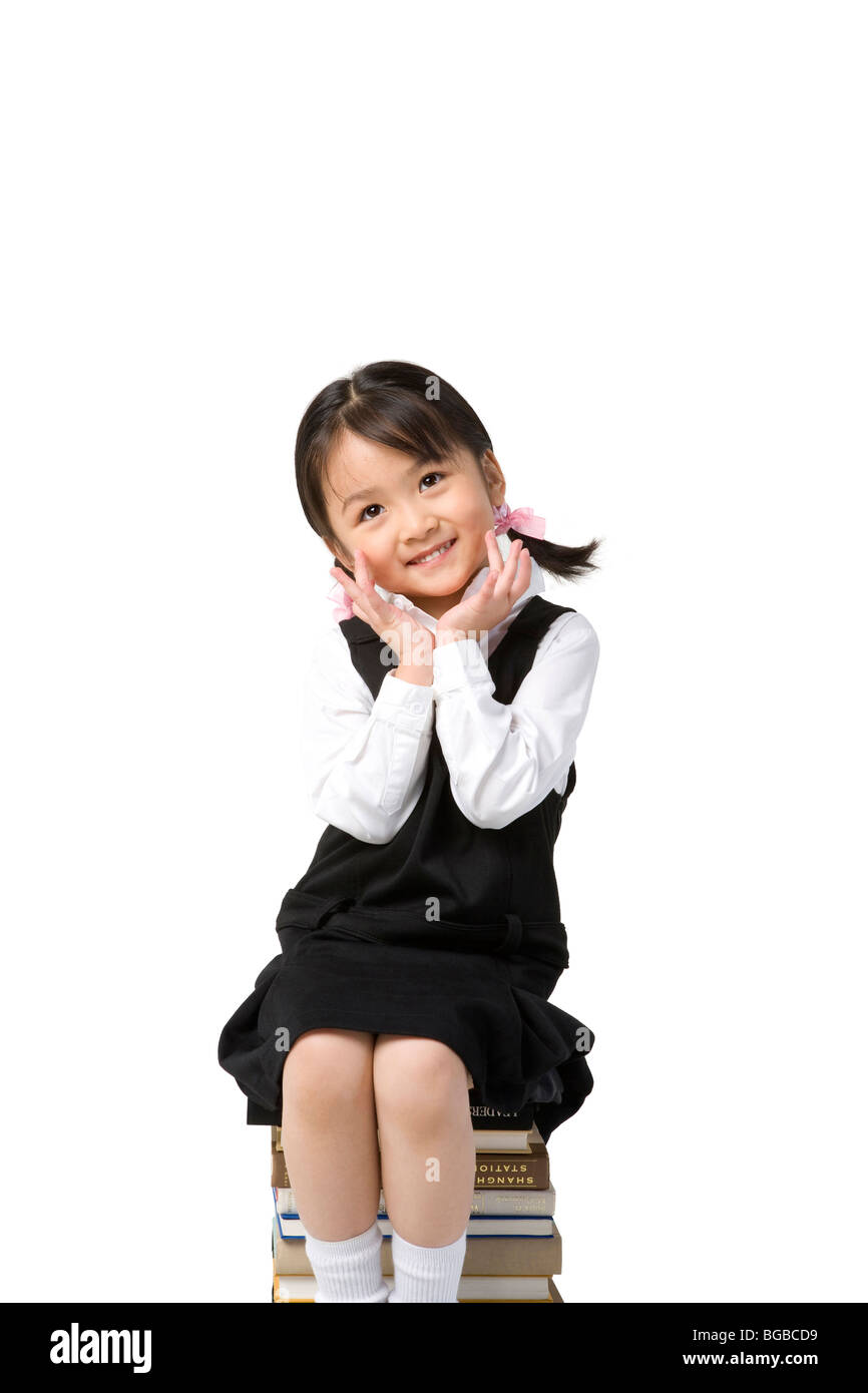 Little girl sits on a pile of books Stock Photo - Alamy