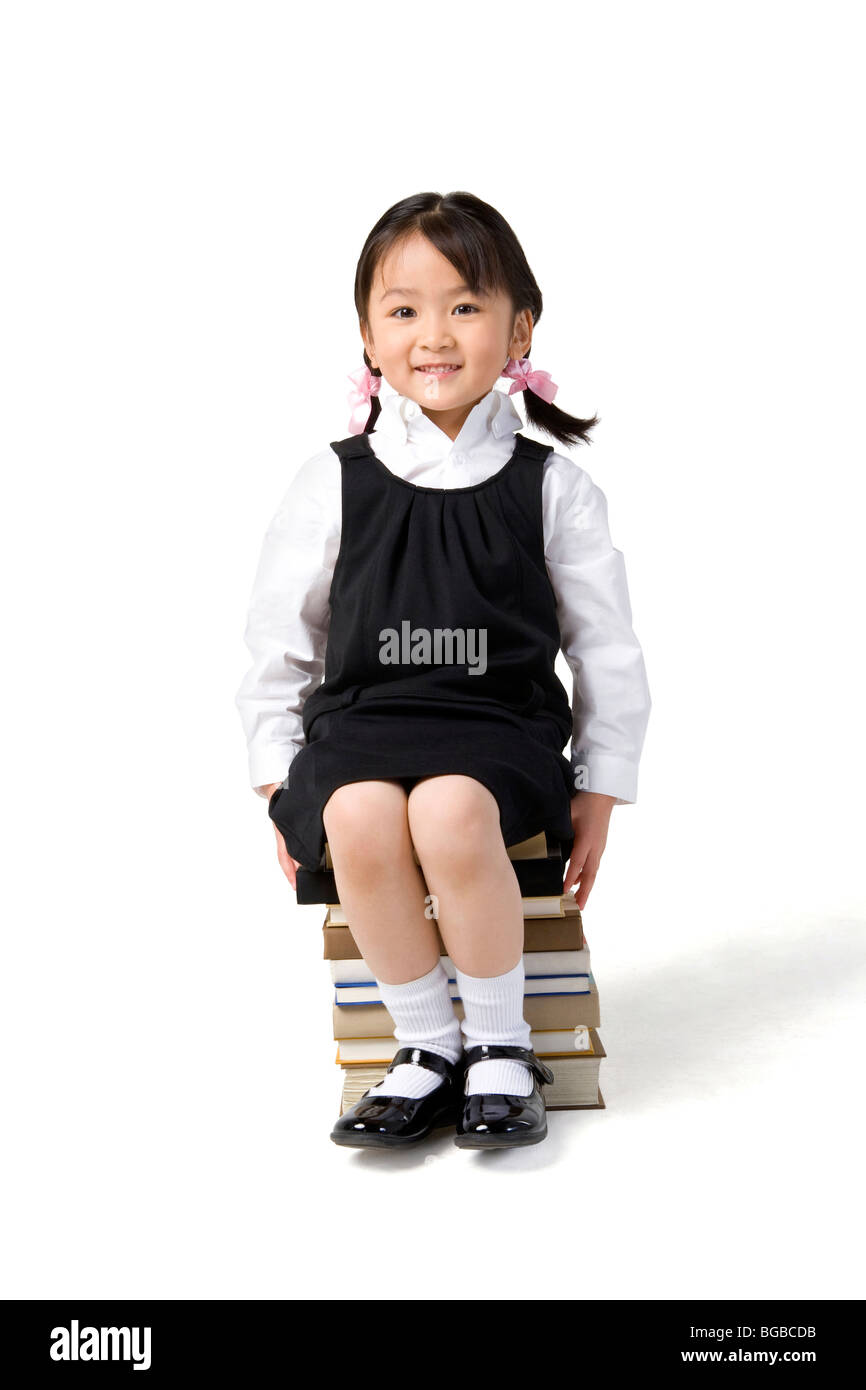 Little girl sits on a pile of books Stock Photo - Alamy