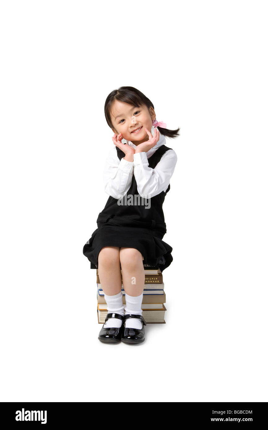 Little girl sits on a pile of books Stock Photo - Alamy