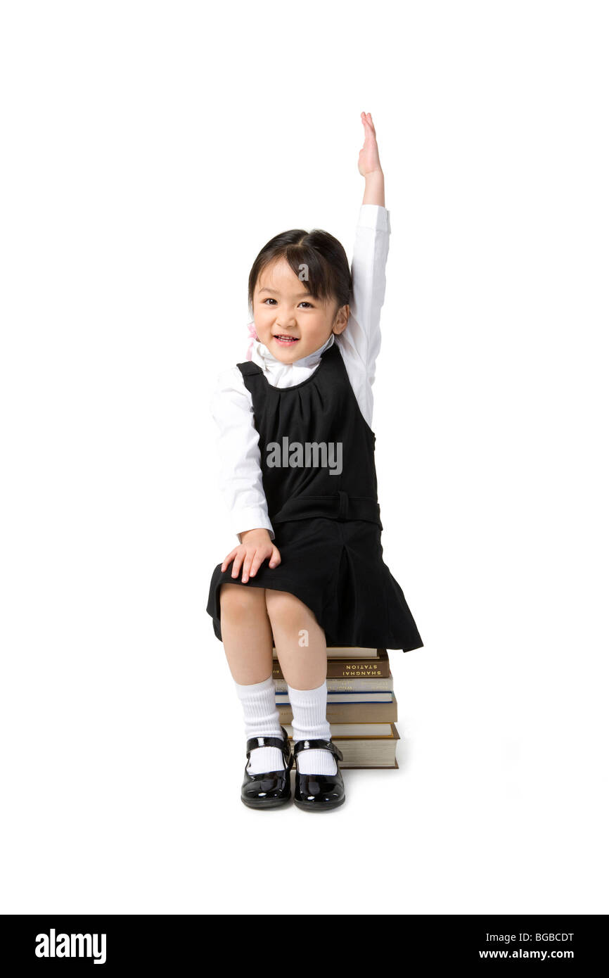 Little girl sits on a pile of books Stock Photo - Alamy