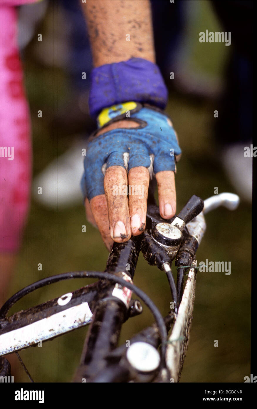 Close up of a cyclists muddy hand on handle bars Stock Photo
