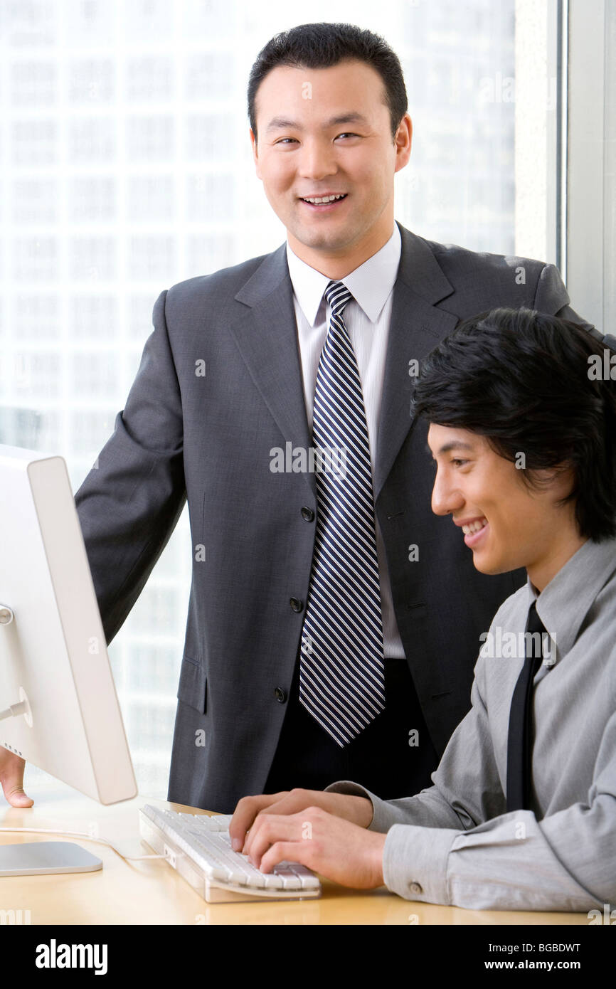 Man in business suit shows young employee something on a computer. Stock Photo