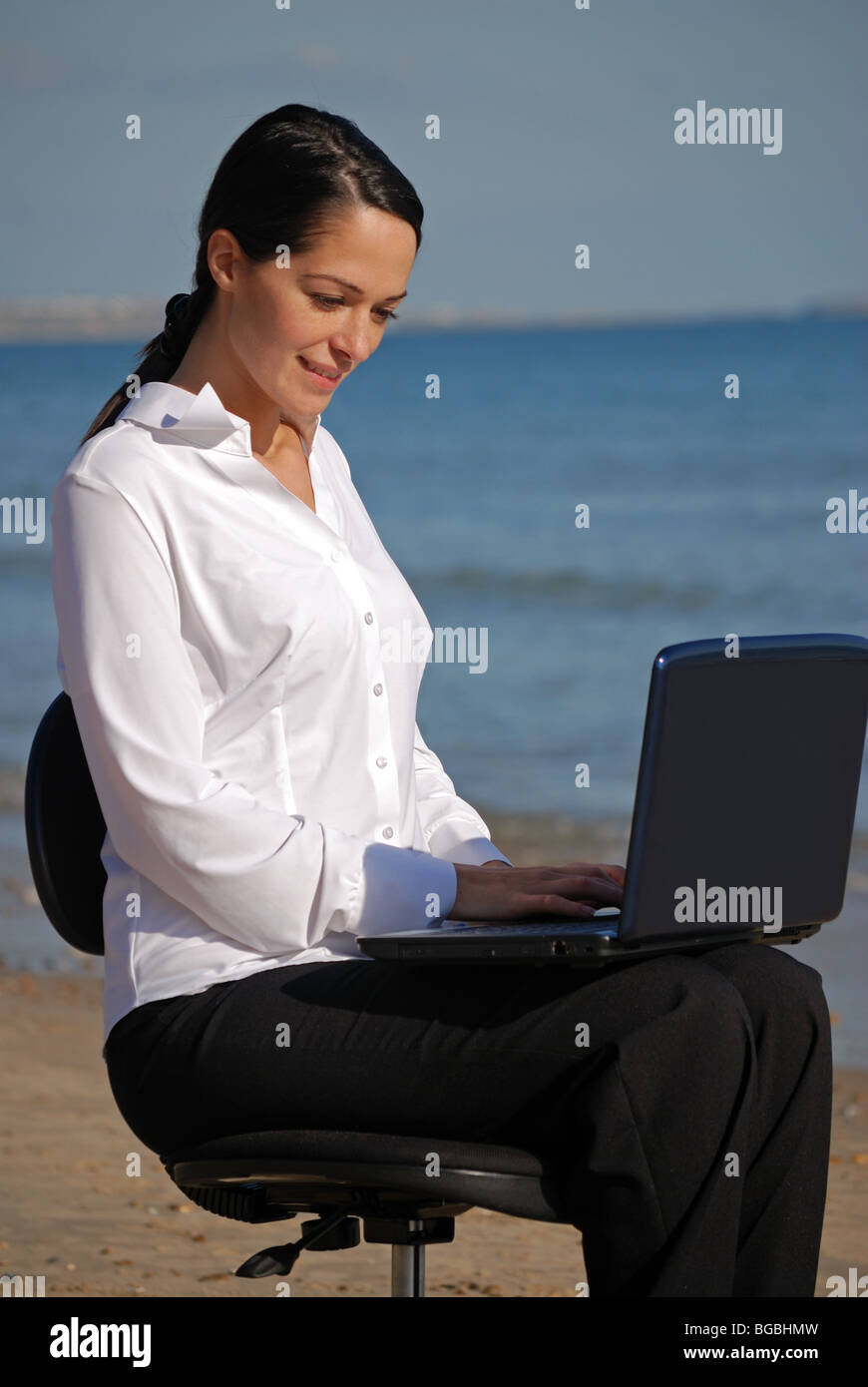 Young woman working on the beach with a laptop Stock Photo - Alamy