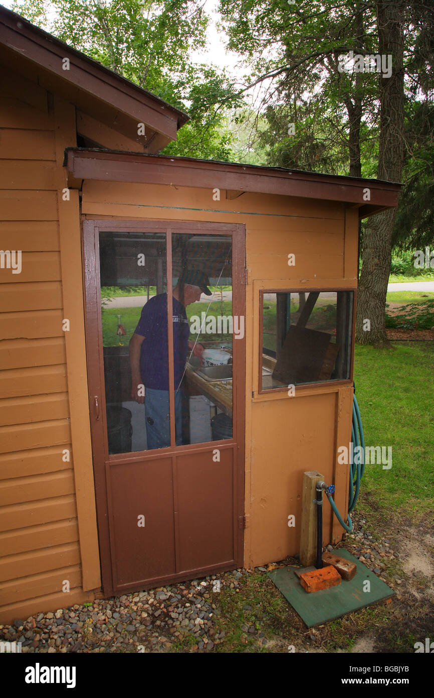 SEASONED FISHING GUIDE FISHERMAN CLEANING FISH IN THE FISH HOUSE BRAINERD LAKES AREA FISHING