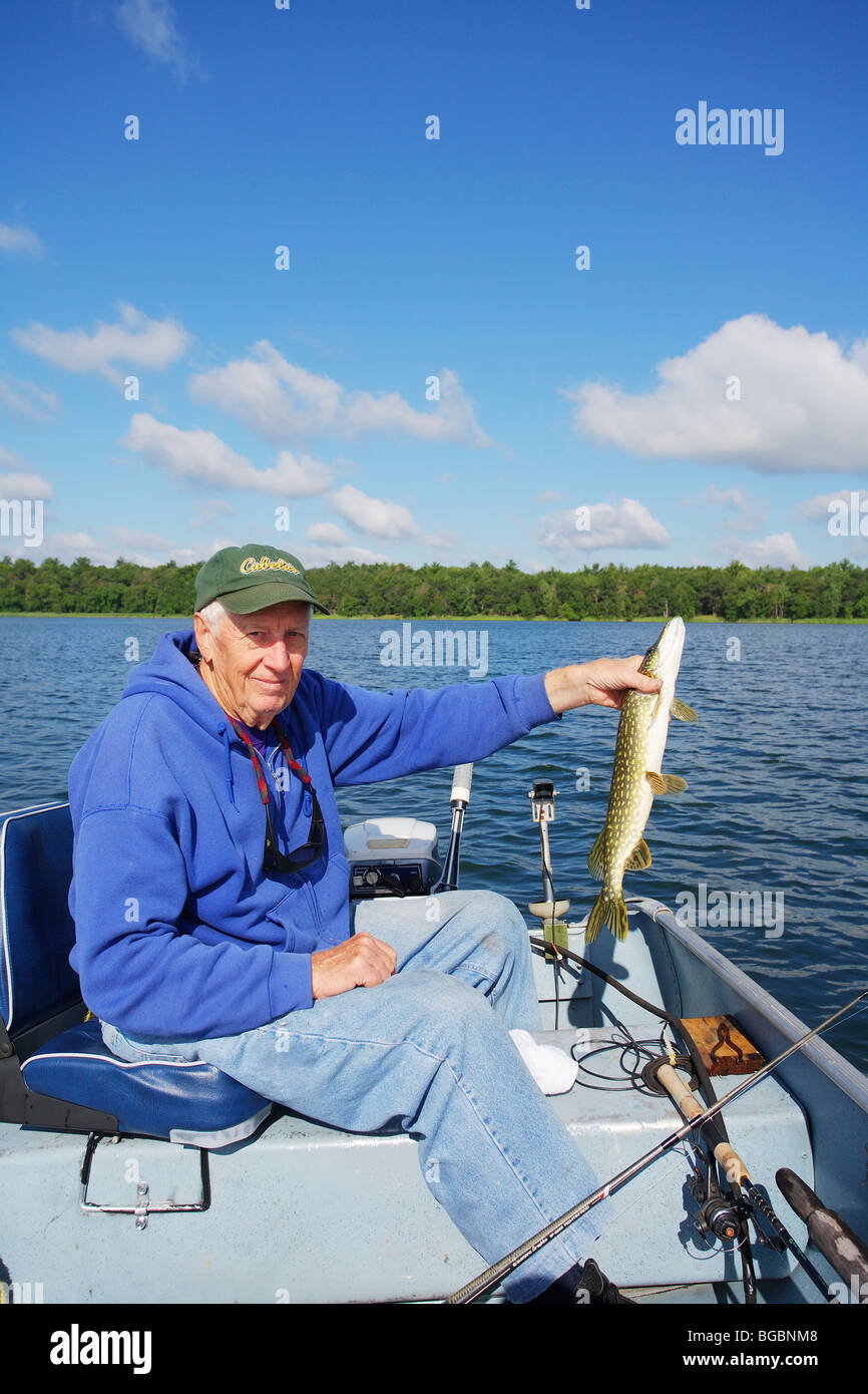 SEASONED FISHING GUIDE FISHERMAN IN ALUMNACRAFT BOAT HOLDING A NORTHERN PIKE Stock Photo