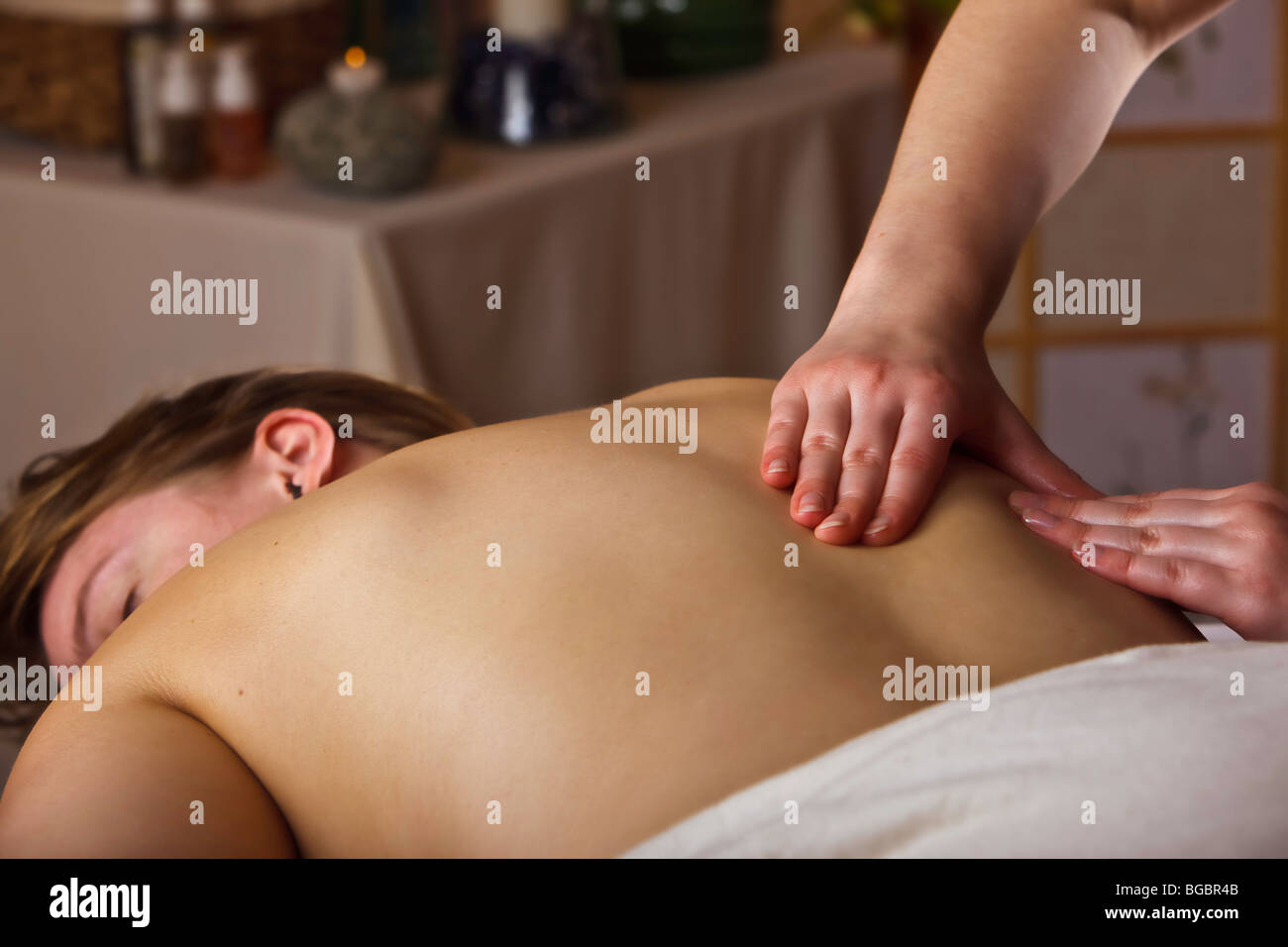Woman lying down enjoying a relaxing back massage by a masseuse. Stock Photo