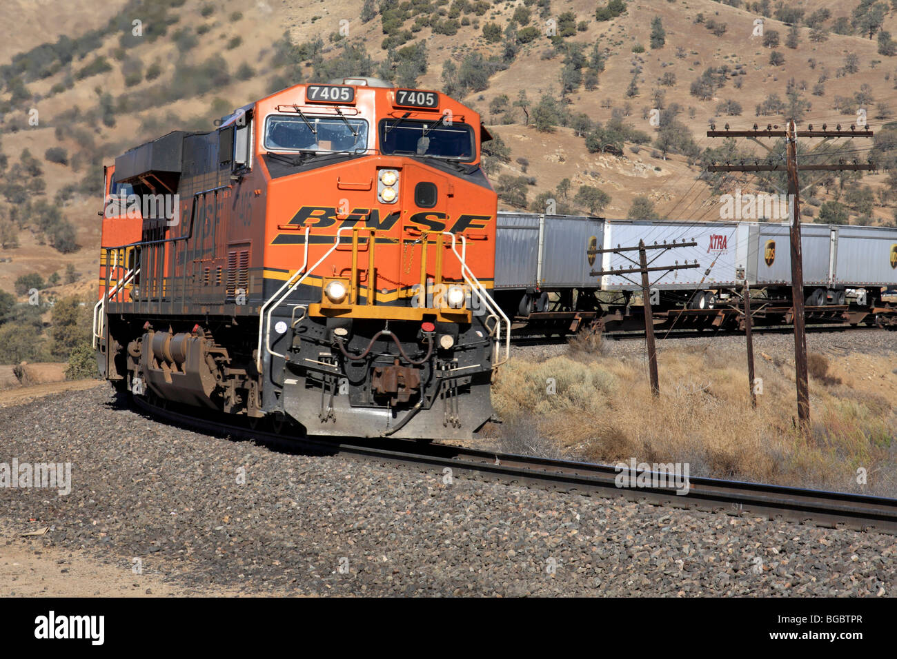 A BNSF freight train led by GE built ES44DC Locomotive 7405 climbs the grade eastbound near the Tehachapi Loop. Stock Photo