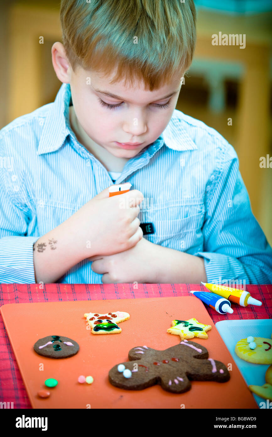 Christmas baking, 7-year-old boy decorating Christmas cookies Stock Photo