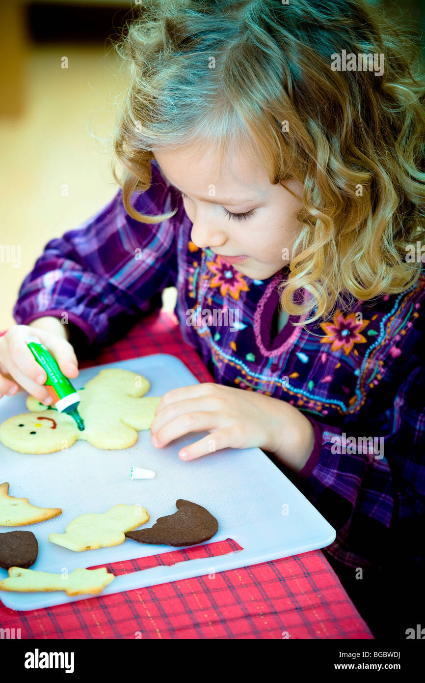 Christmas baking, 7-year-old girl decorating Christmas cookies Stock Photo