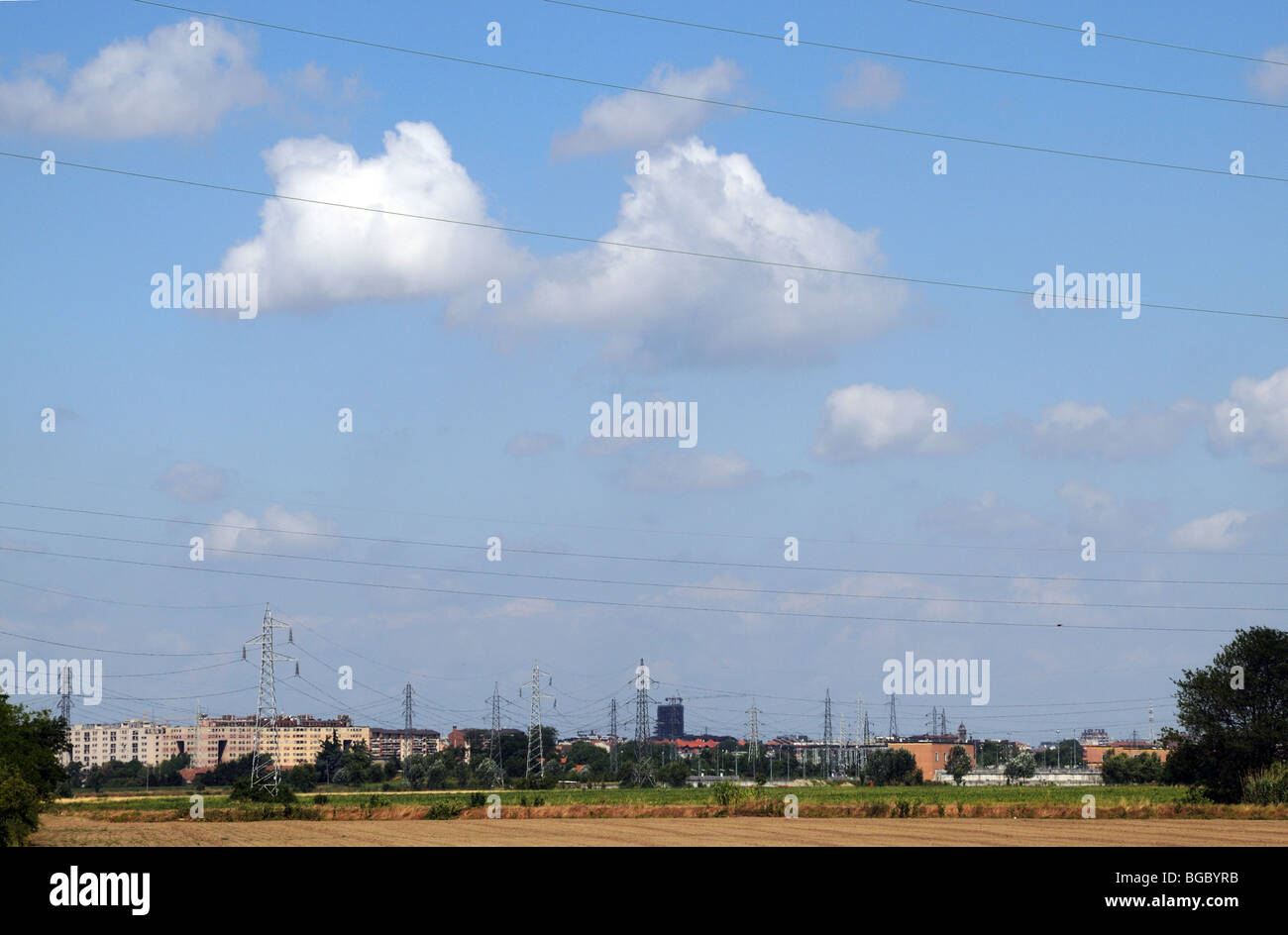 High voltage power cables wires and pylons crossing farm land in the foreground Southern periphery of Milan Lombardy Italy Stock Photo
