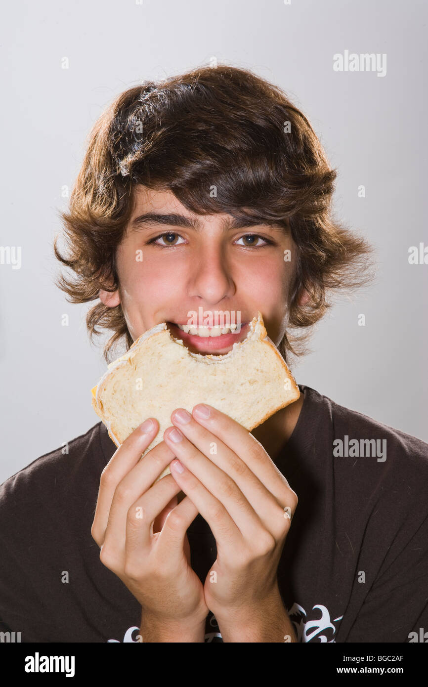 Teenage boy eating ham and cheese sandwich, Studio, Portrait Stock