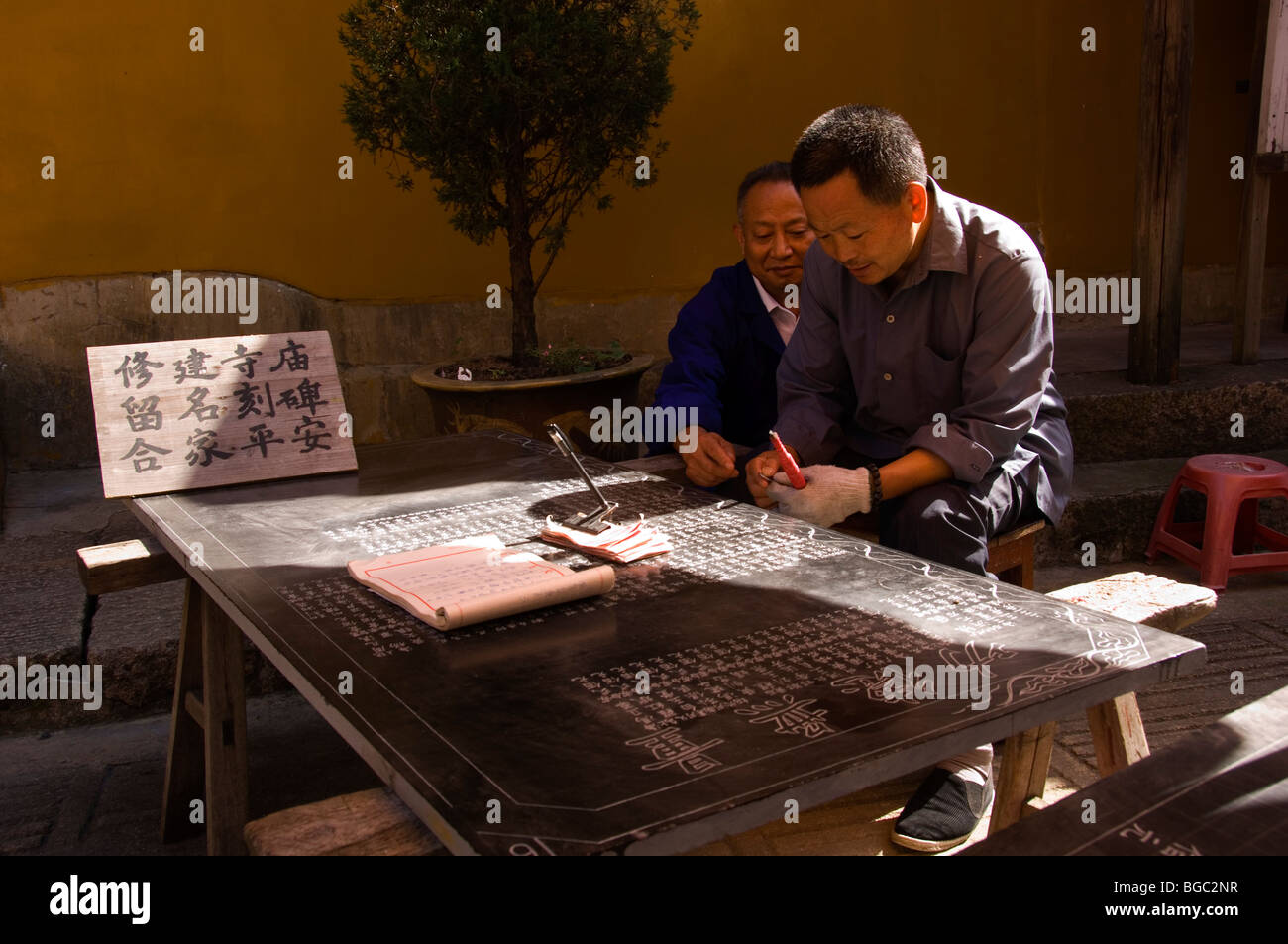 Man engraving the names of contributors of the Zhiyuan temple on a stone tablet. Jiuhua Shan. Anhui province, China. Stock Photo