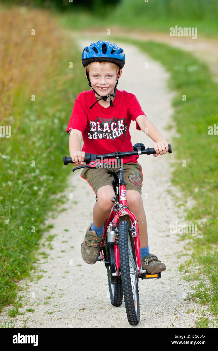 A boy, 7 years, riding a bicycle on a dirt road Stock Photo