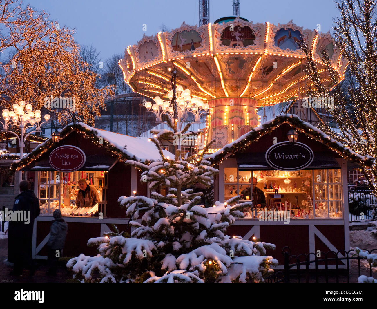 Funfair and small wooden craft shops at dusk at Christmas market in Liseberg amusement park in Gothenburg Sweden Stock Photo