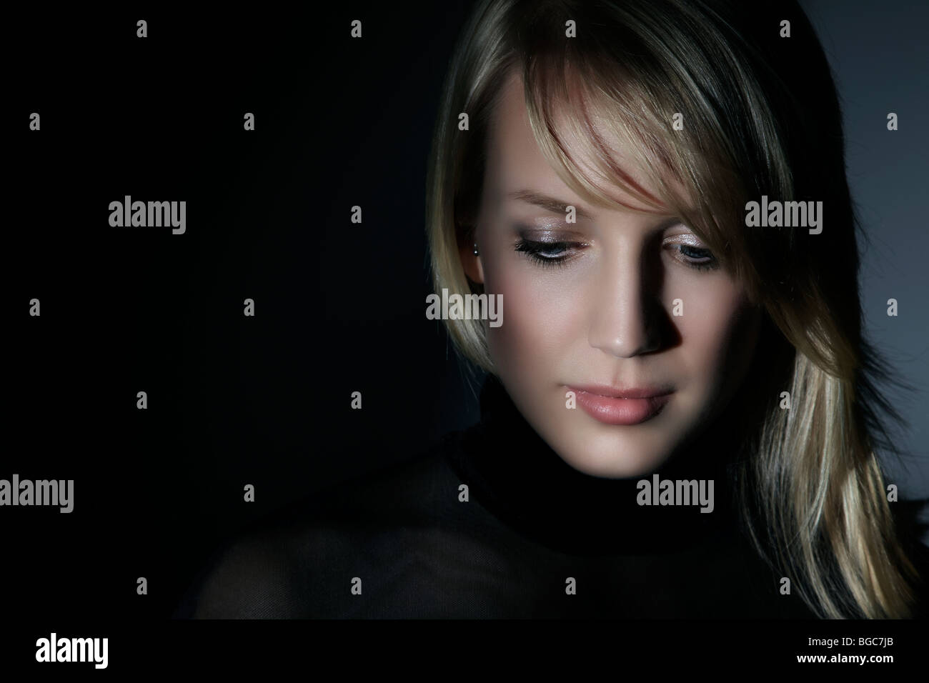 Young woman, surrounded by shadows, looking down Stock Photo - Alamy