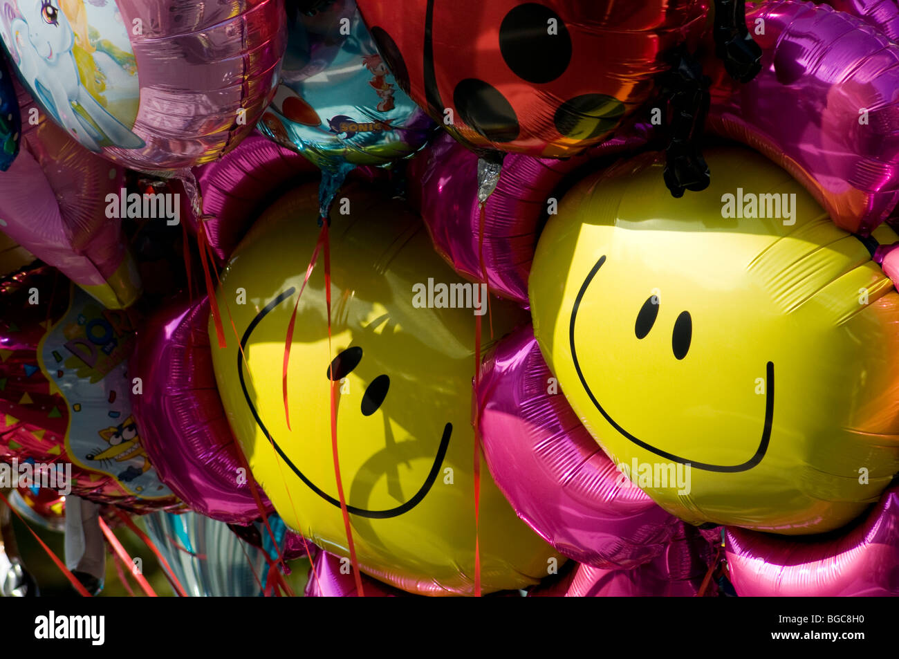 Smiley face balloons surrounded by other helium balloons , Tavistock, Devon Stock Photo