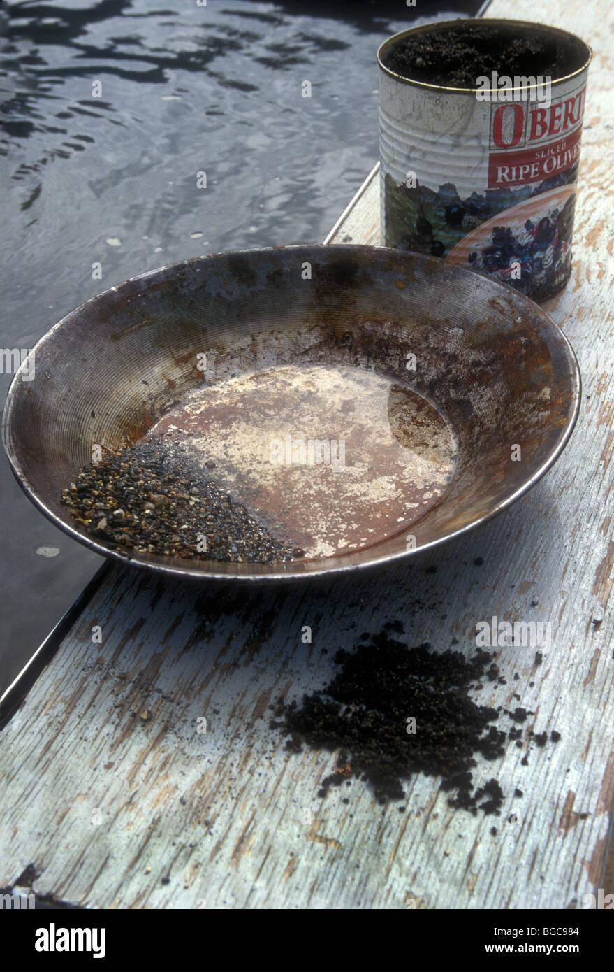 Gold pan with river gravel and gold flakes. Alaska USA Stock Photo
