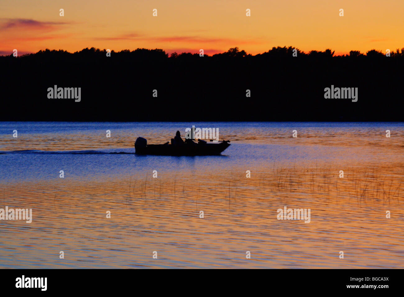 silhouette two fisherman in boat on lake at sunset Stock Photo