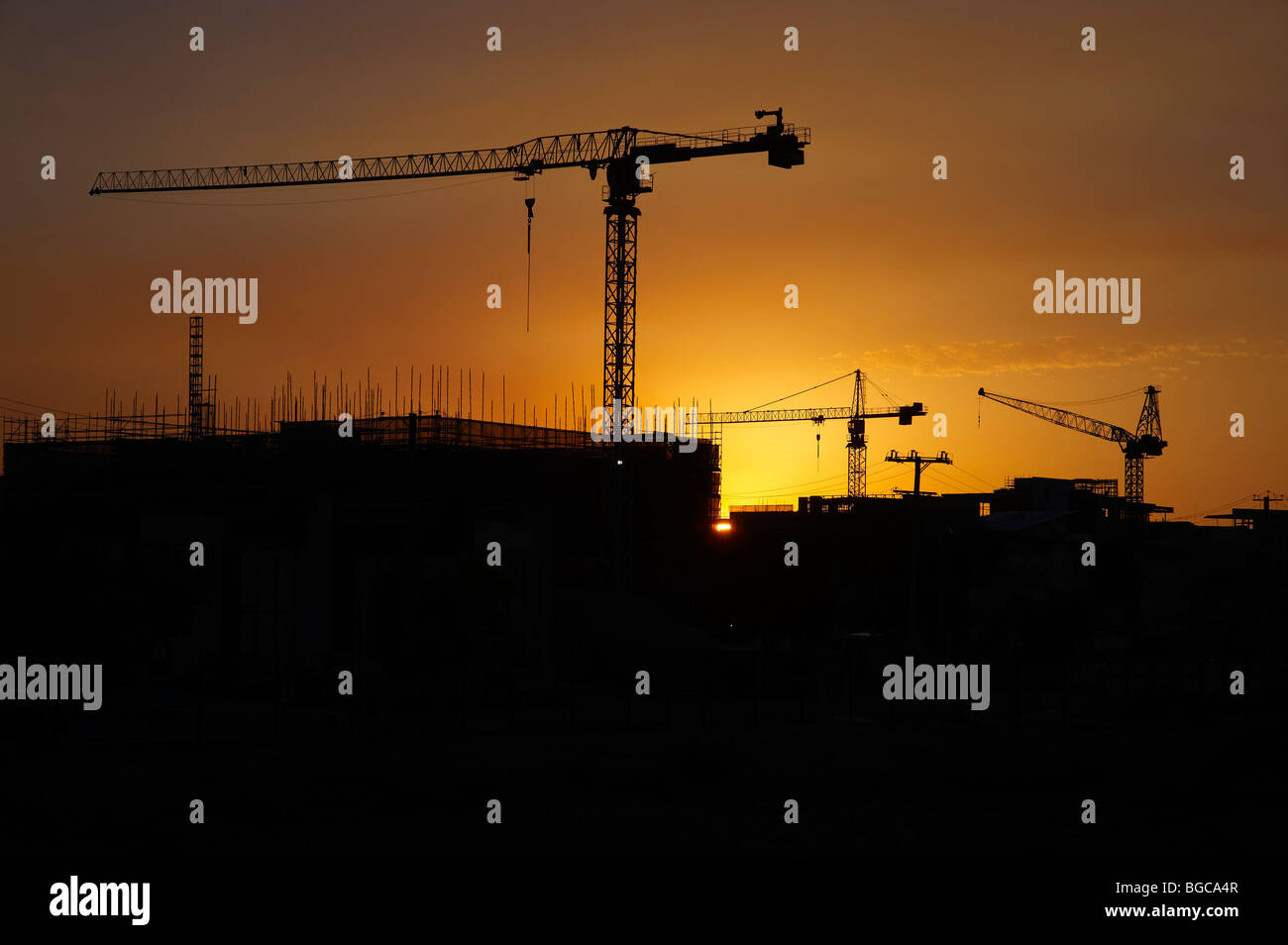 Tower cranes silhouetted on a construction site Stock Photo