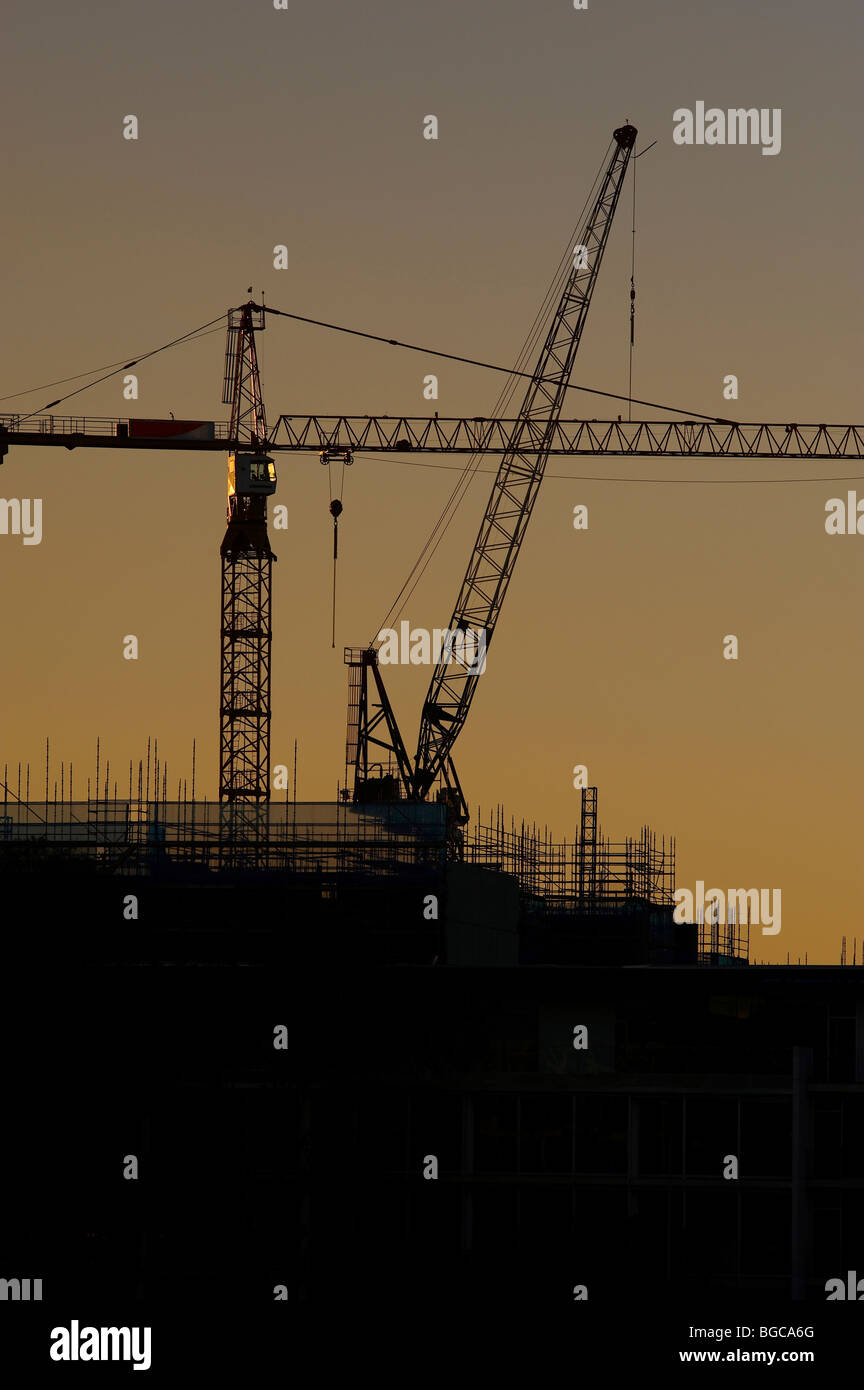 Tower cranes silhouetted on a construction site Stock Photo