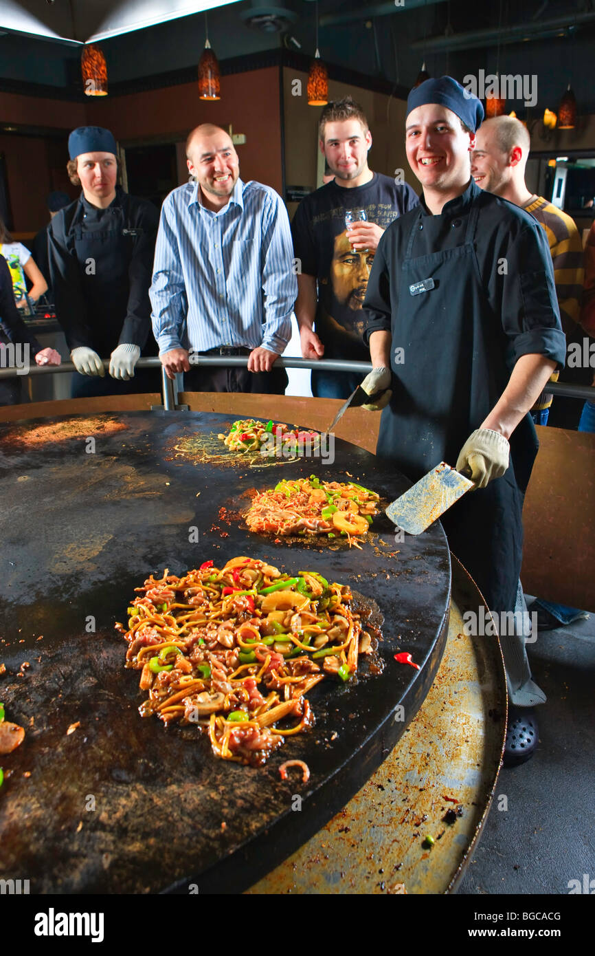 Chef preparing meals while guests gather around to watch at the Mongolie Grill World Famous Stirfry Restaurant in Whistler Villa Stock Photo