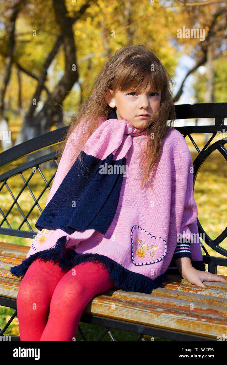 Little girl sitting on a bench in the park Stock Photo - Alamy