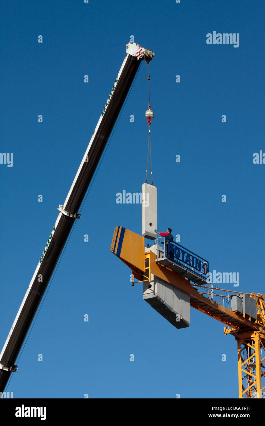 A construction worker stands on a crane waiting to dismantle it at a just finished apartment block Tenerife Canary Islands Spain Stock Photo
