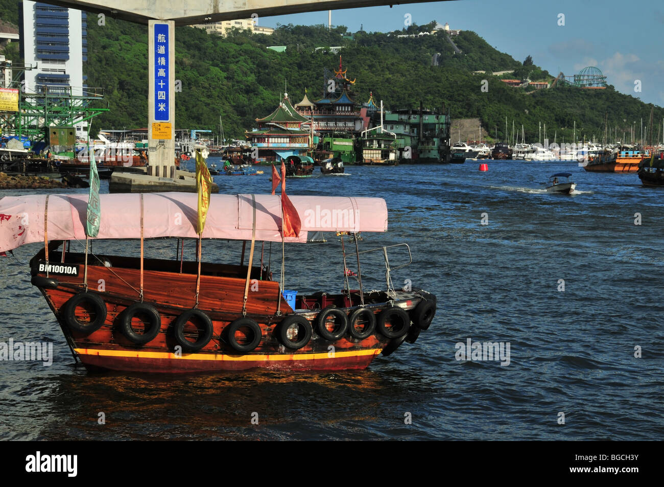 Sampan, pink canopy and flags, moored in front of the Ap Lei Chau Bridge and Jumbo Restaurant, Aberdeen Harbour, Hong Kong Stock Photo