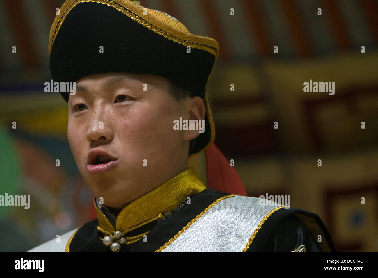 A young Mongolian man sings in the style of Khoomi or throat singing wearing traditional