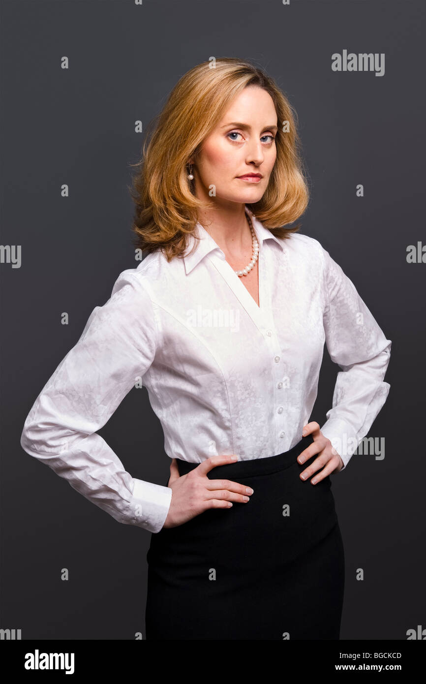 Portrait of a blonde woman wearing a white jacquard shirt on a grey background Stock Photo