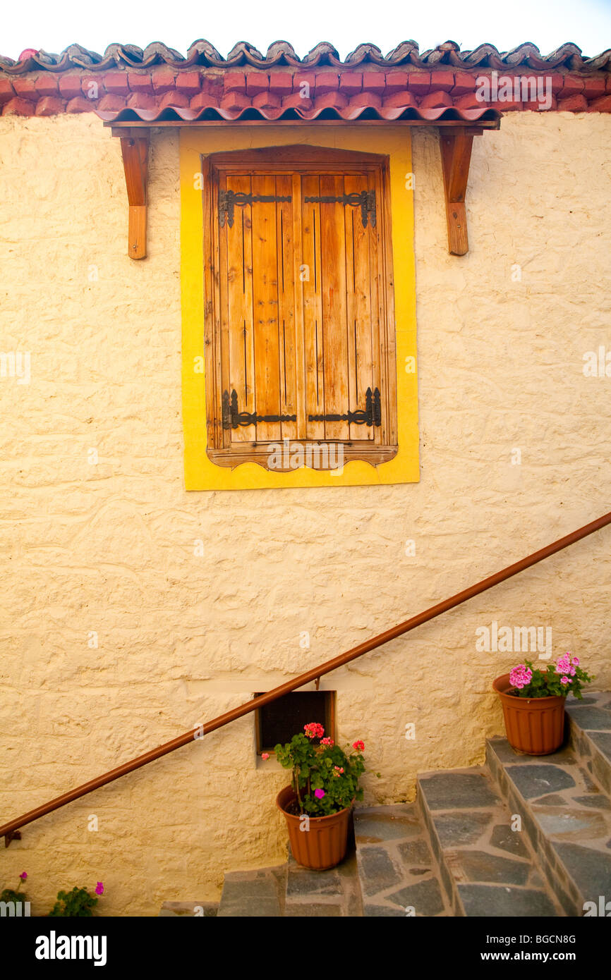 A closed shuttered window stands in the wall of a house above stone ...