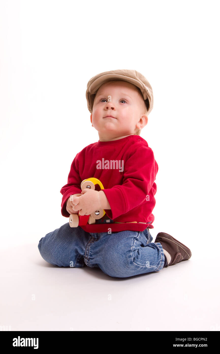 1 year old little boy   wearing big cap plays with toy cars isolated on white Stock Photo