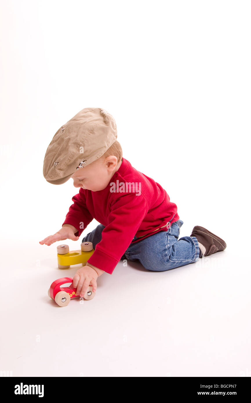 1 year old little boy  wearing big cap plays with toy cars isolated on white Stock Photo