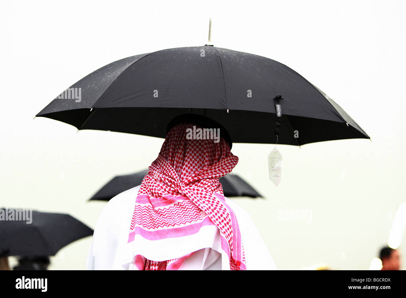A man in traditional clothing under an umbrella, Dubai, United Arab Emirates Stock Photo