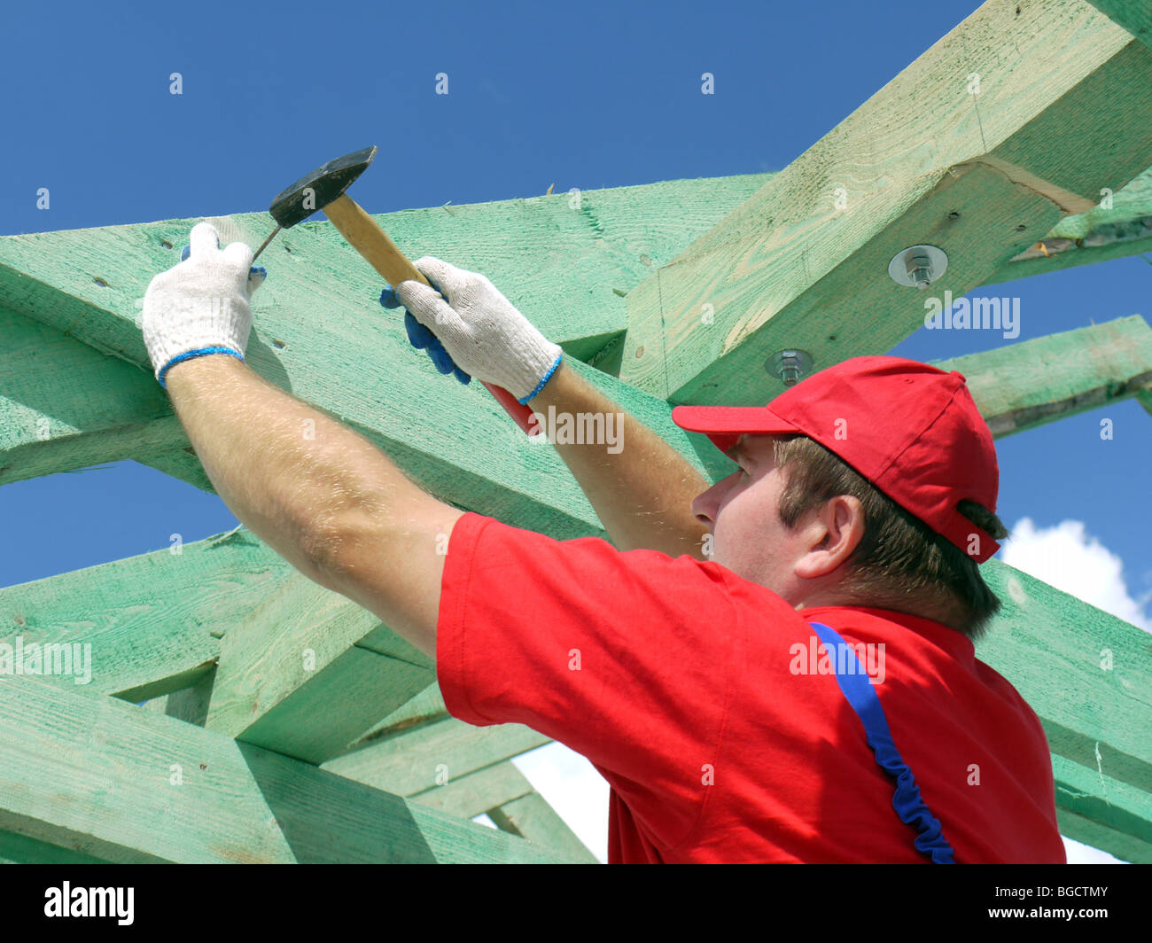 Carpenter driving a nail into house rafter framing beam Stock Photo