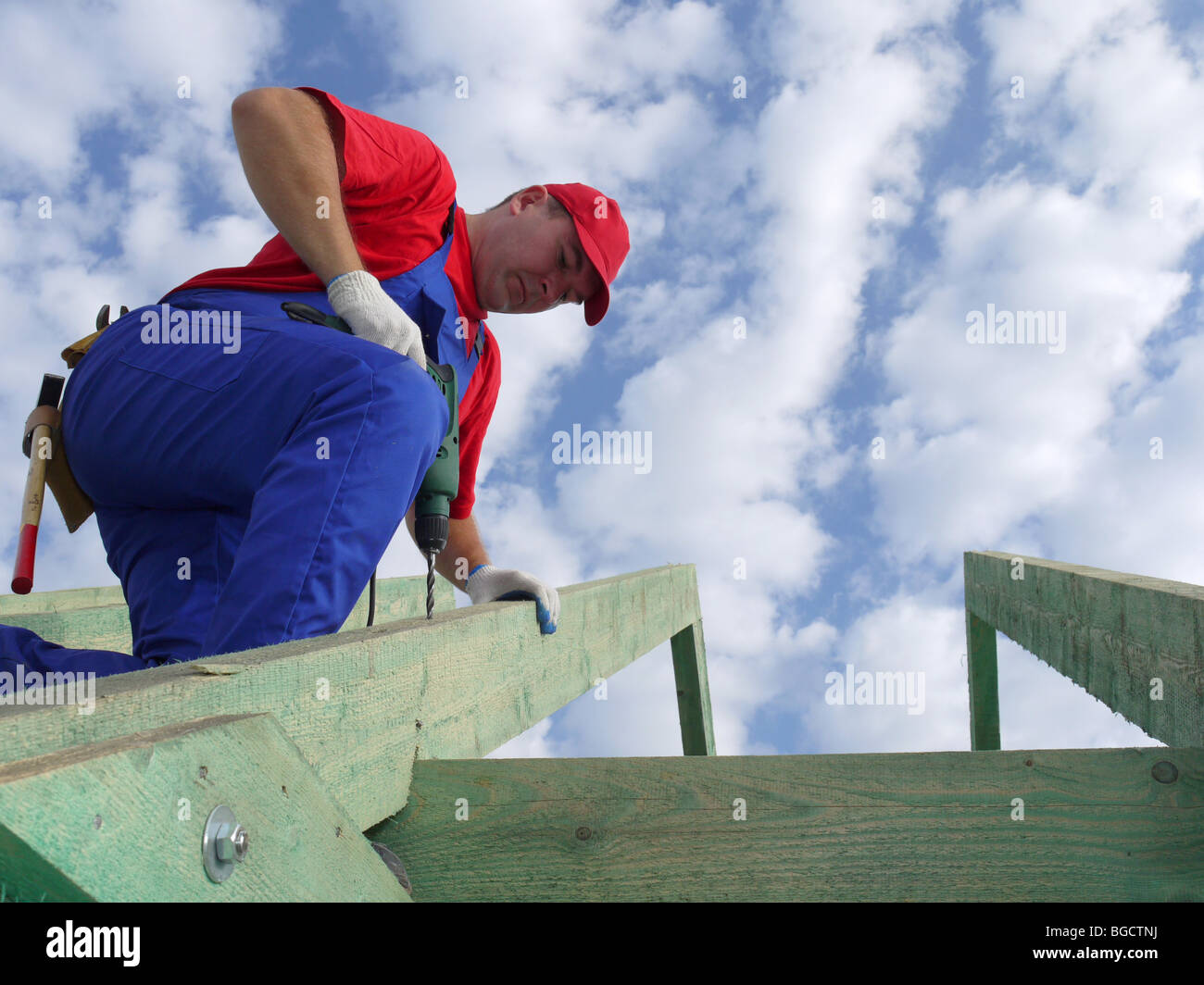 Carpenter drilling a hole in rafter framing beam Stock Photo
