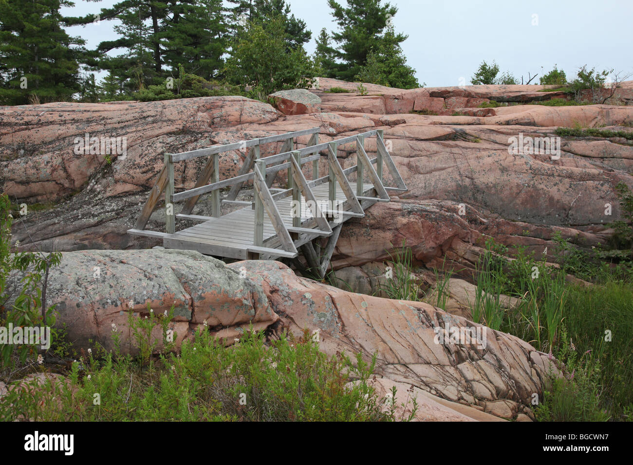 wooden bridge among pink granite rocks Stock Photo