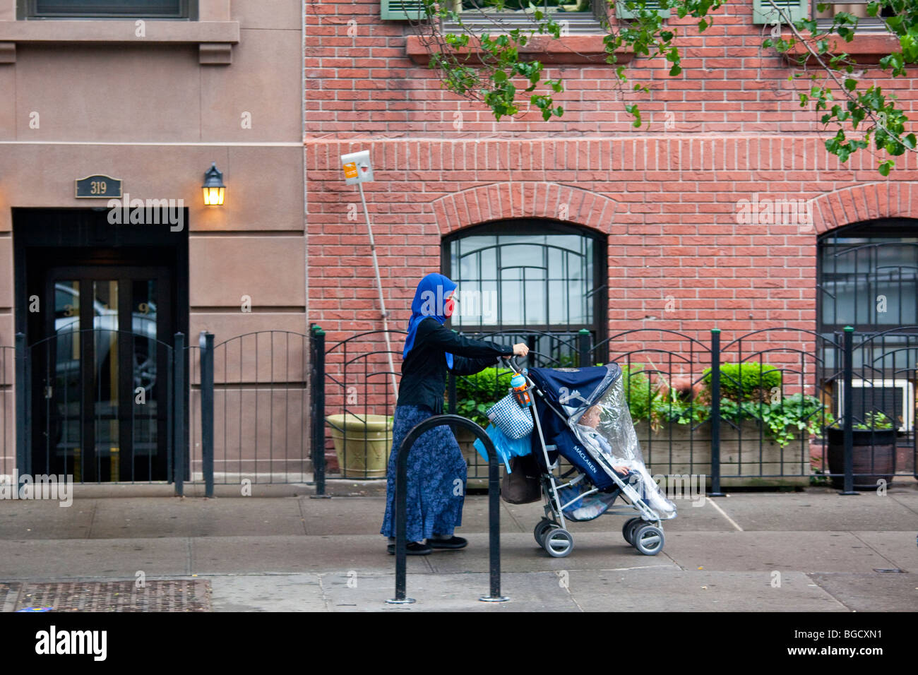 Indonesian nanny pushing a baby in New York City Stock Photo