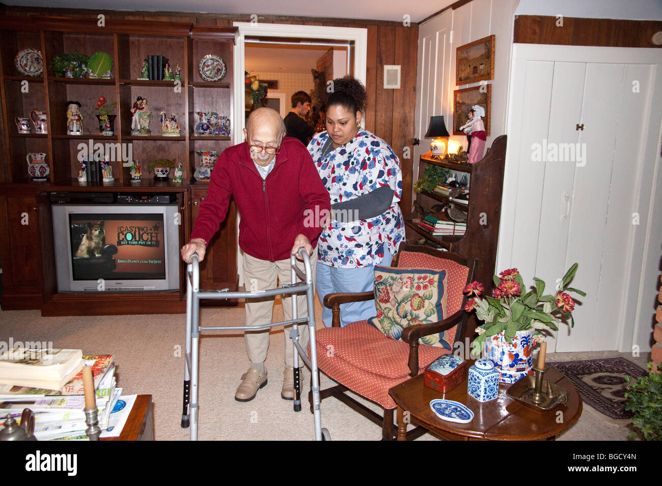 Home health care worker helps elderly man use his walker. Stock Photo