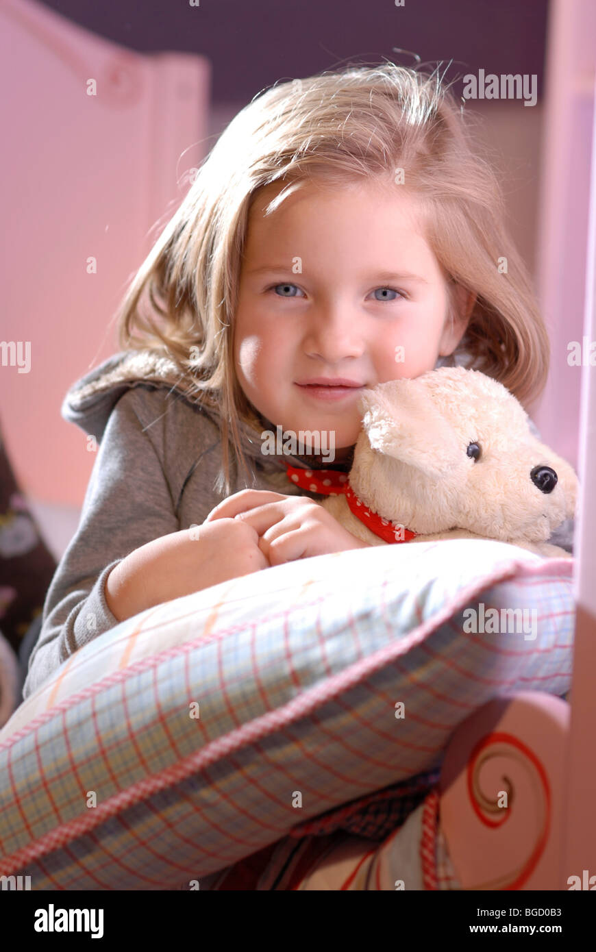 Little girl with her soft toy lyubg between pillows in her bed Stock
