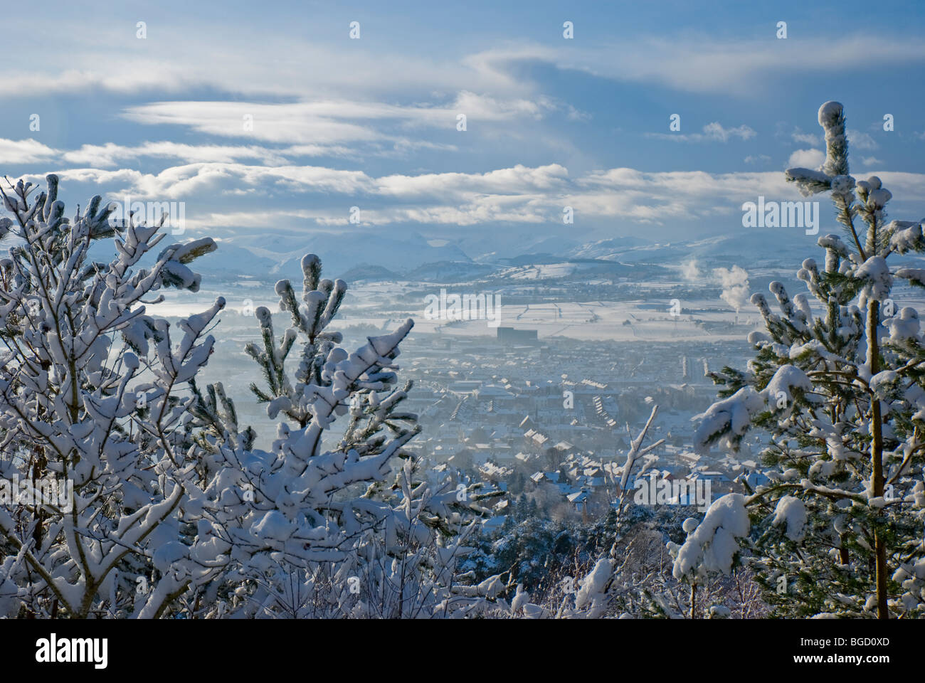 A view of Penrith and surrounding Lake District mountains through snow covered trees from Beacon Hill Stock Photo