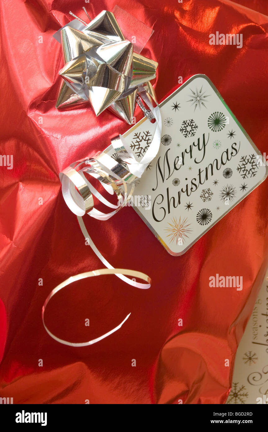 Silver Bow Ribbon and A Merry Xmas Label On Red Christmas Wrapping Paper Stock Photo