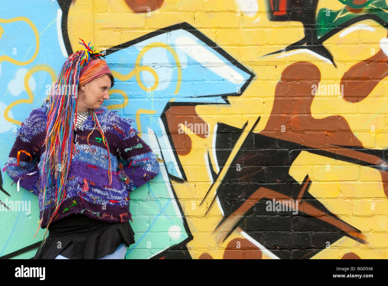 Young female hippy with multi coloured hair against graffiti wall FULLY MODEL RELEASED Stock Photo