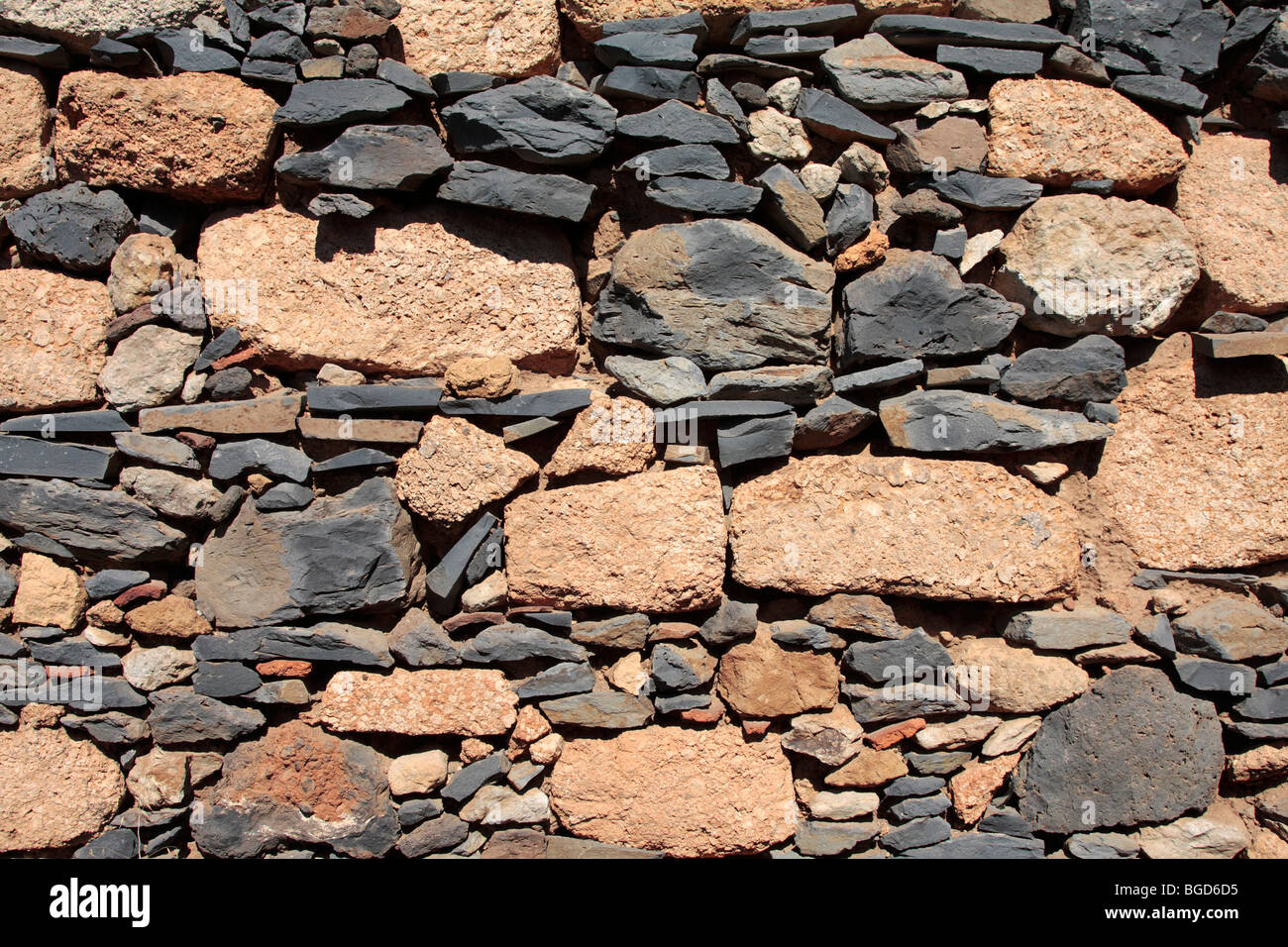 Various types of volcanic stone used in the building of an exterior house wall and hand made roof tiles in the old village Stock Photo