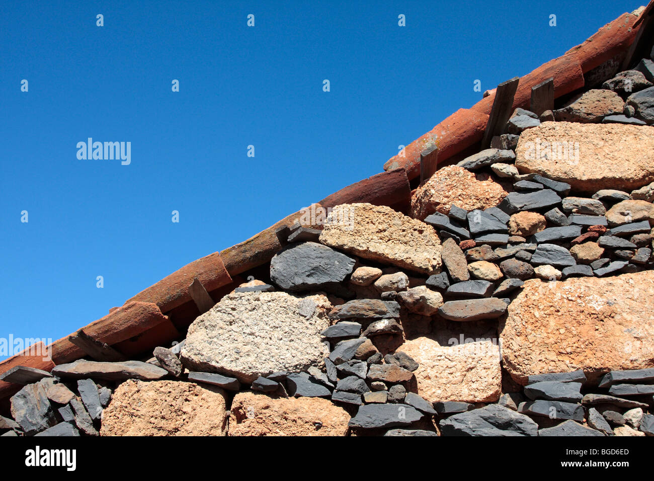 Various types of volcanic stone used in the building of an exterior house wall and hand made roof tiles in the old village Stock Photo
