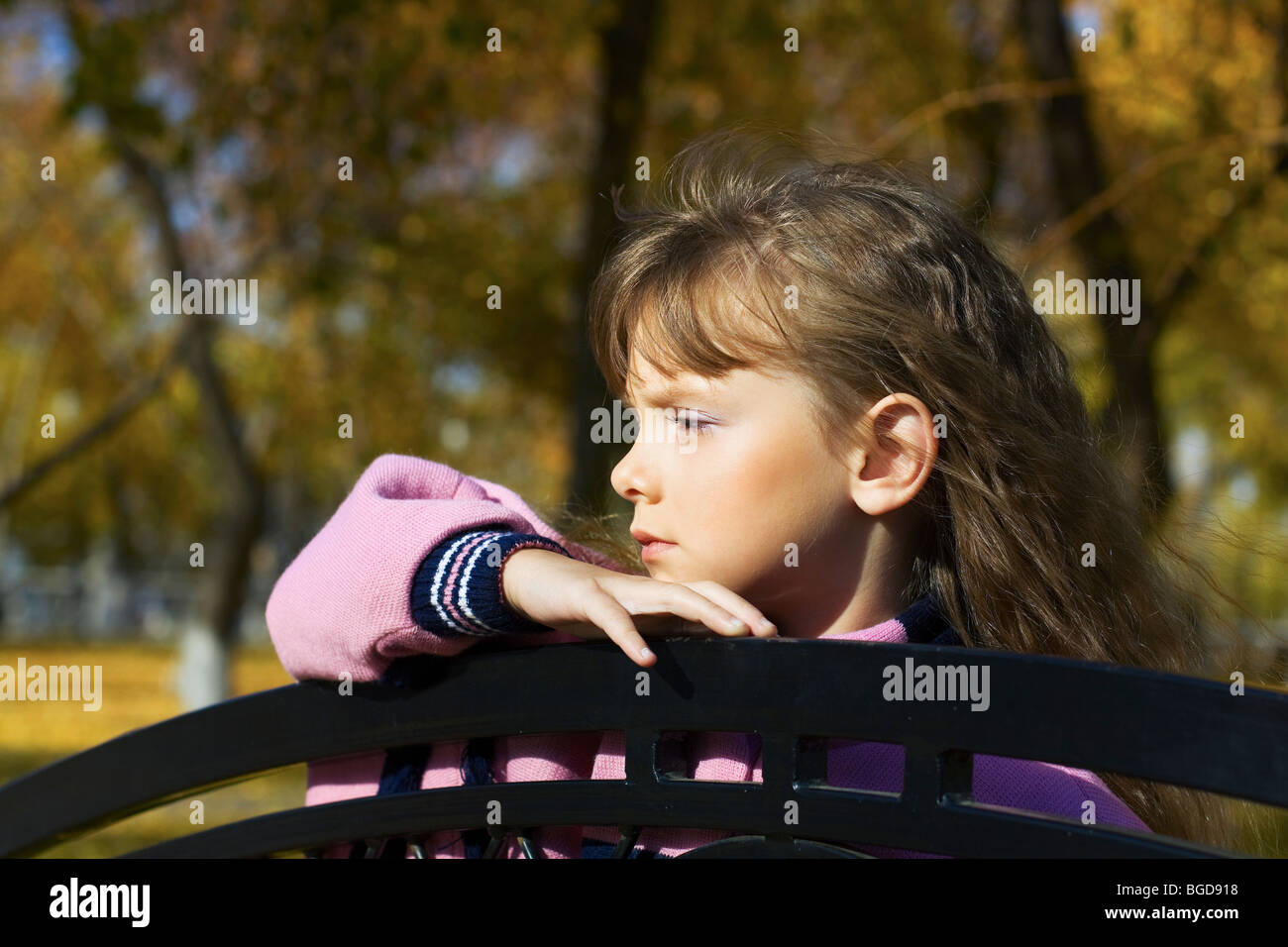 Thoughtful little girl leaning on a bench in the park Stock Photo - Alamy