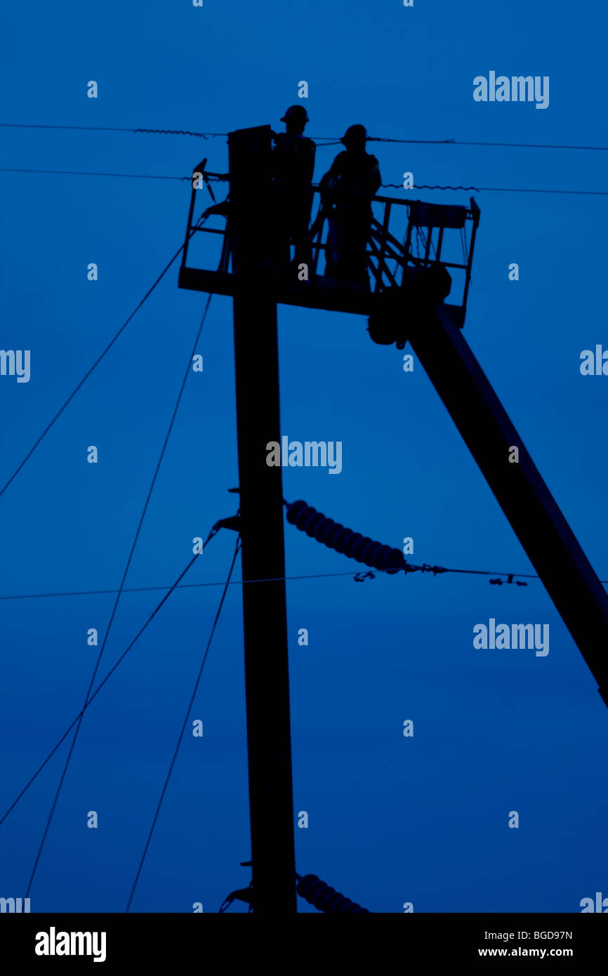 Electrical linemen working out of a bucket on power lines Stock Photo