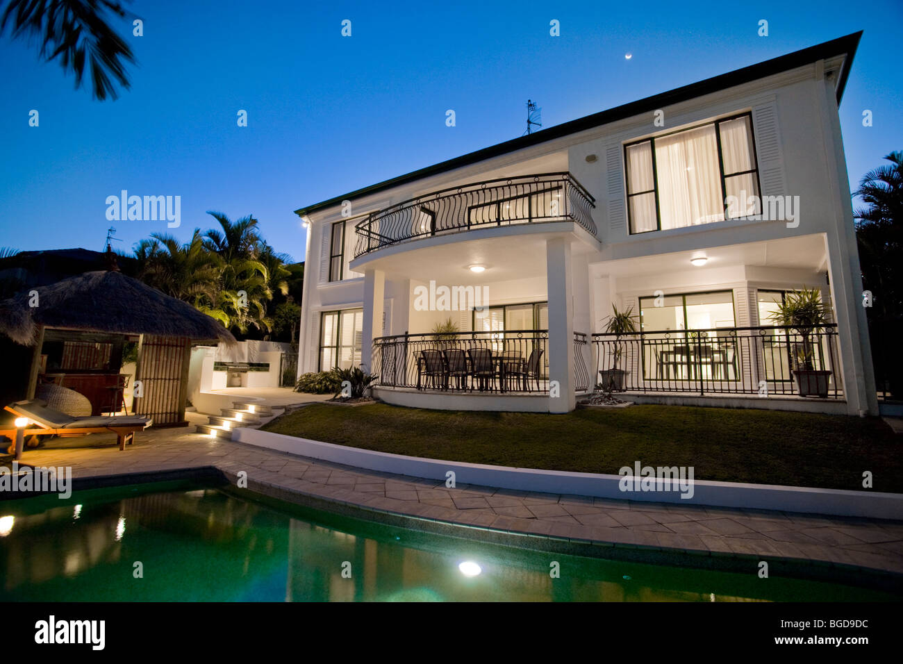 Luxurious mansion exterior at dusk overlooking pool Stock Photo