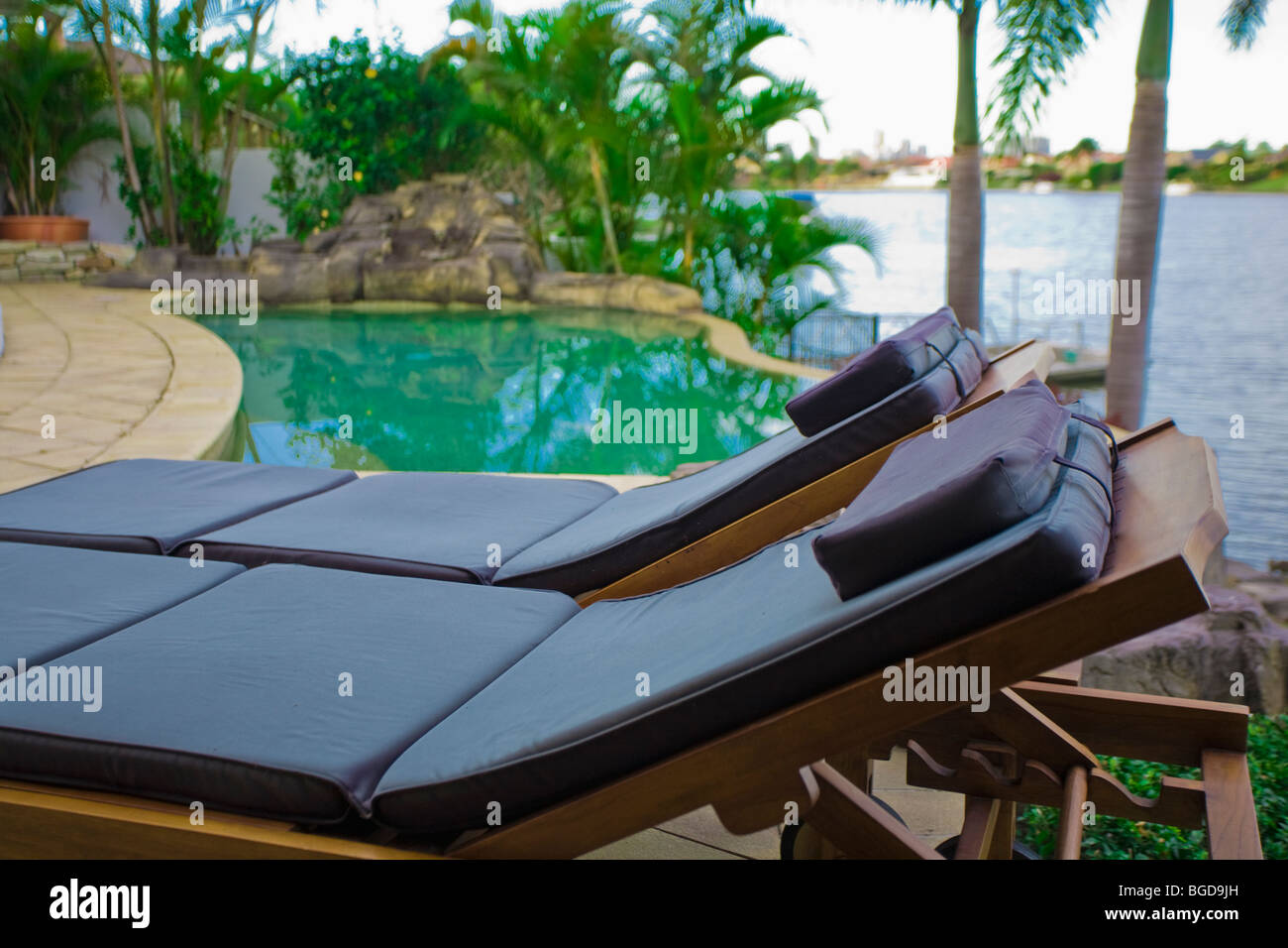 Deck chairs by the pool at tropical waterfront mansion Stock Photo Alamy