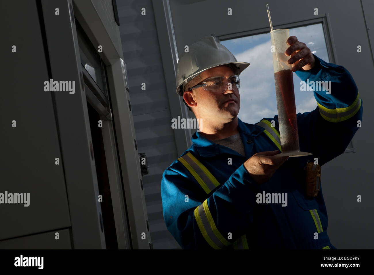 a petroleum worker looking at a liquid test in a column Stock Photo